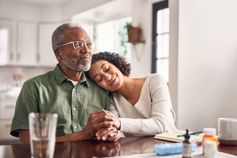 A young woman rests her head on an older man's shoulder