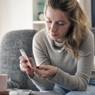 A young woman checks her blood sugar at home.