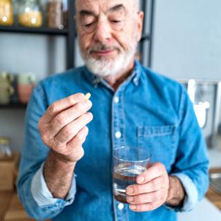 A man examines a pill in his hand, wondering if it can be split safely.