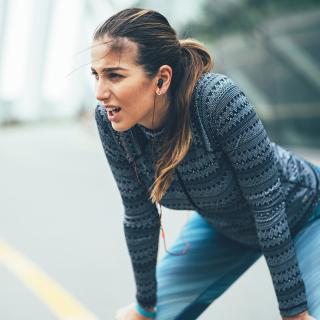 A young woman stops on her run outside to catch her breath.