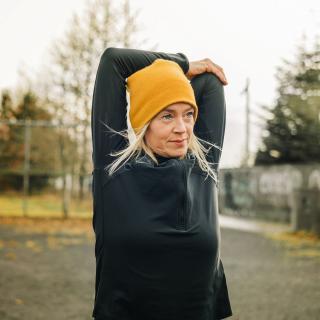 A woman stretches her arms outside before her workout.